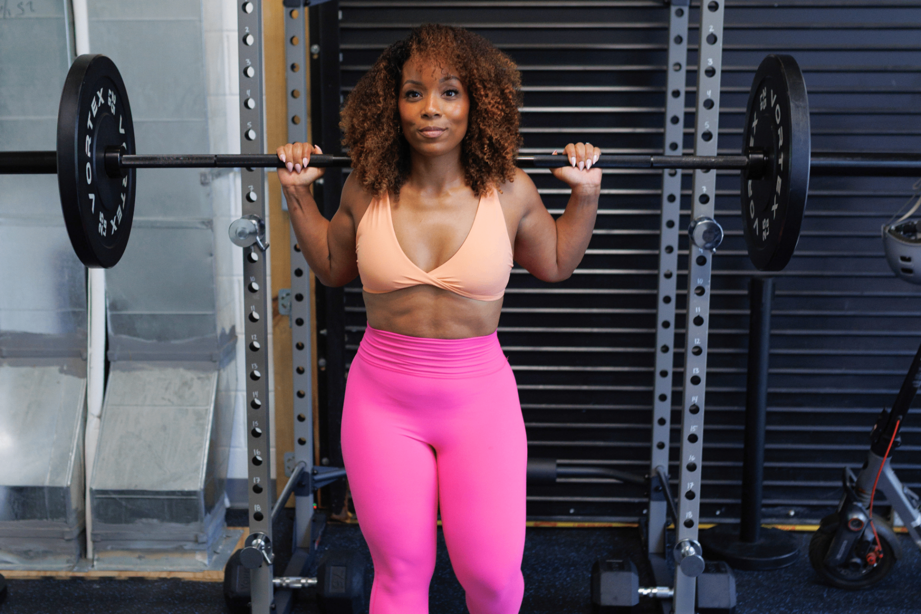 Jelisa holding a barbell across her shoulders in the gym